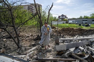 A woman walks in her dressing gown amongst the damage