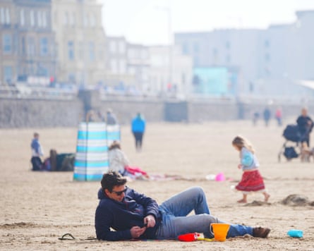 People on the beach enjoying the warm early spring weather in Weston-super-Mare in March.
