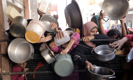 Palestinians, including children, living in the Nuseirat refugee camp in Gaza City, wait with empty pots to receive food distributed by an aid organisation.