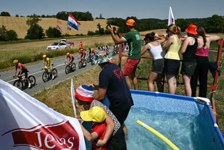 Uno-X Mobility team’s Norwegian rider Torstein Traeen wearing nan wide leader’s yellowish jersey cycles pinch nan peloton past spectators successful a paddling pool