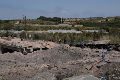 नष्ट हुए पुल के पास मलबे पर चलते लोग।