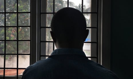 A man looks out of a window covered in bars