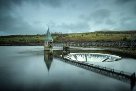 Pontsticill reservoir’s circular overflow drain under cloudy skies