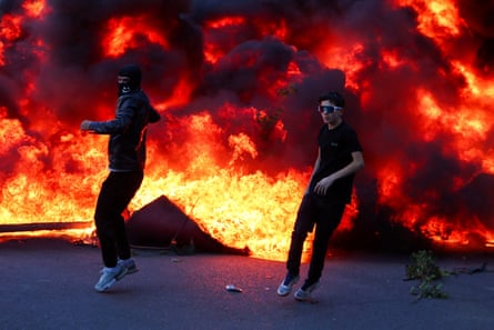 Two people run from a wall of flames.