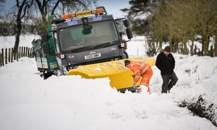 Men clear snow around a plough stuck in a drift in Lamancha, Scotland