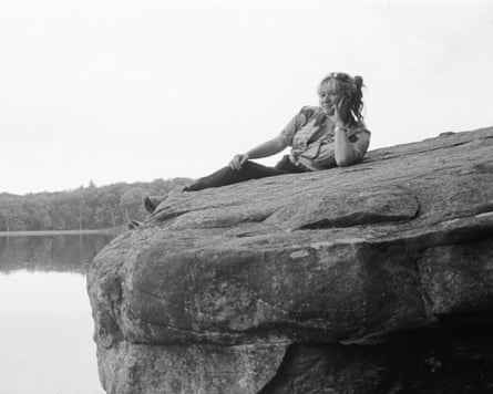 A black and white photo of Wendy Eisenberg reclining on a rock