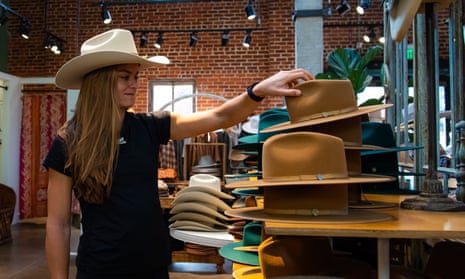 woman looks at hats on shelf while wearing hat