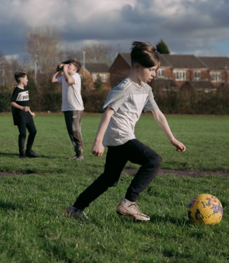 A boy running with a football with friends playing in the background
