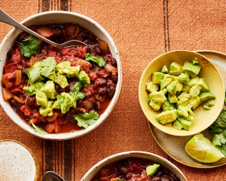 Rukmini Iyer’s spiced black bean and tomato soup with avocado and lime in bowls on table