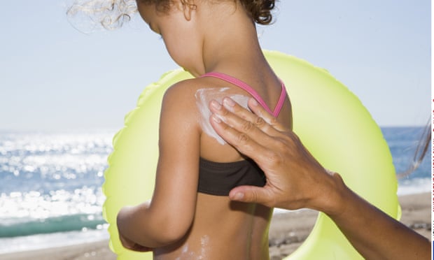 Parent applying sunscreen to child's back