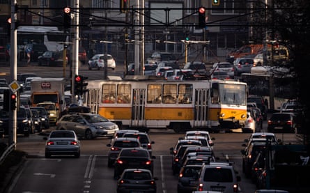 A tram crosses an intersection in front of three lanes of waiting cars