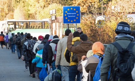 refugees cross the border from Germany into Austria to bord a bus