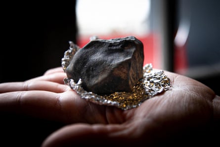 A piece of black rock on a piece of tin foil in someone’s spread palm.