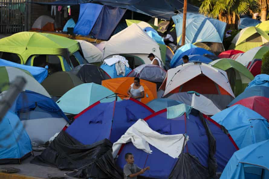 People wake up at a camp near a legal port of entry bridge in Matamoros, Mexico