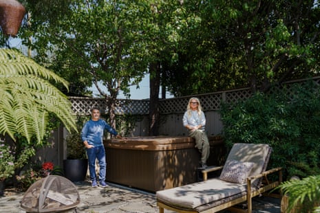 A woman and man standing a backyard, leaning against a covered hot tub.