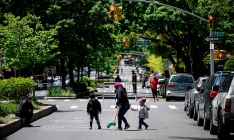 A woman plays with two children on a street, closed to cars during a pilot program to provide more space for social distancing amid the pandemic, in Queens, New York.