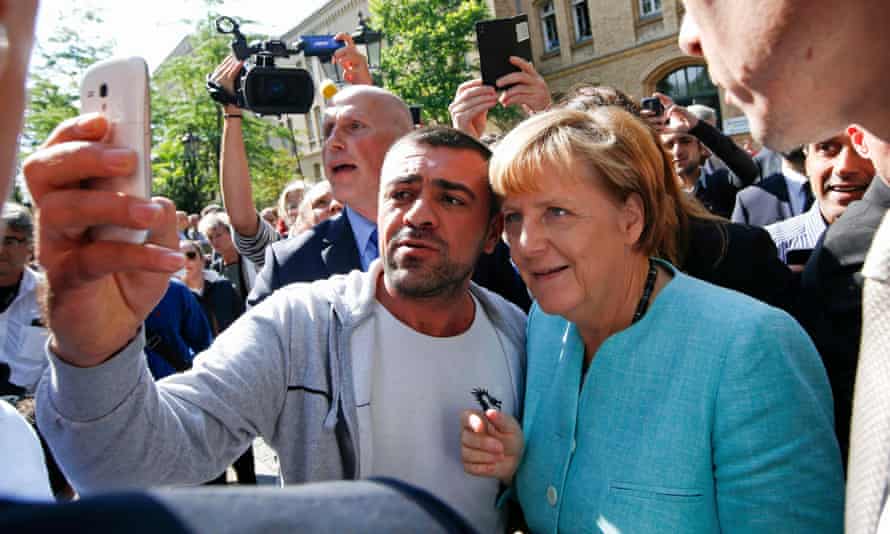 A man takes a selfie with Merkel outside a refugee camp in Berlin in 2015.