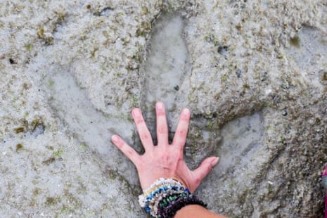 Broome woman Bindi Lee Porth places her hand in the dinosaur tracks she discovered on Sunday at Cable beach in Broome, Western Australia. The tracks, which were buried in the sand, were last reported in 1974.
