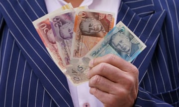 A man holds up four banknotes bearing King Charles's face