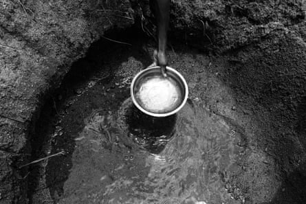 Albertina, 10, scoops water from a hole dug in the dry Lurio riverbed, in M’mele village