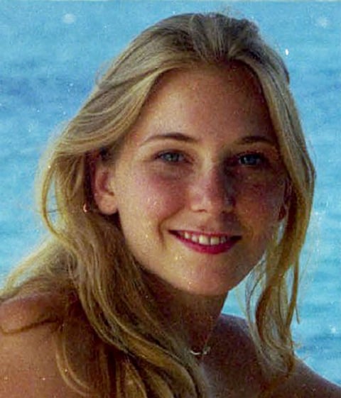 A close up picture of a young blond woman with the sea behind her
