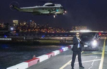 A Secret Service agent stands guard as a helicopter carrying Barack Obama prepares to land in New York