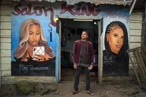Clovis, 22, poses in front of his hairdressing salon in Goma