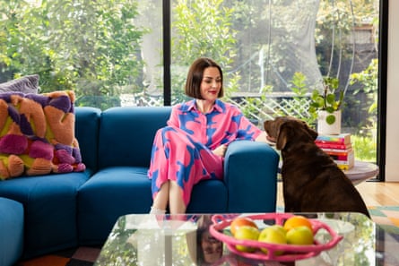 Cherie Clonan sitting on a blue couch in her bright, light living room with her pet dog.