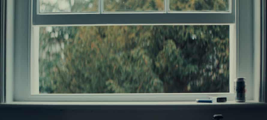 An open sash window with leafy trees beyond it.