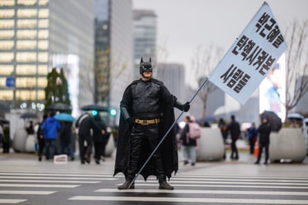 An anti-Yoon protester dressed as Batman holds a flag that reads: ‘Those who experienced impeaching Park Geun-hye’, at a rally outside Gyeongbokgung Palace in Seoul last April.