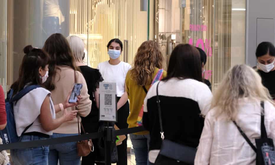 Queue of shoppers with masked retail worker