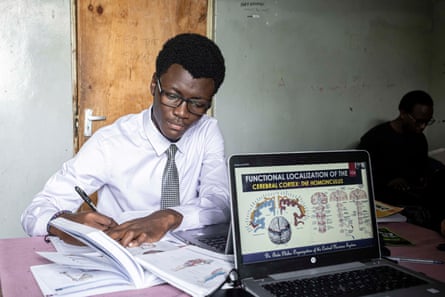 Carl Mwangi studies with textbooks and a laptop.