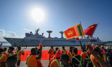 Workers wave the flags of Sri Lanka and China to welcome the Chinese research and survey vessel the Yuan Wang 5 at port in Hambantota