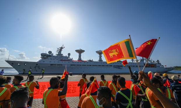 Workers wave the flags of Sri Lanka and China to welcome the Chinese research and survey vessel the Yuan Wang 5 at port in Hambantota