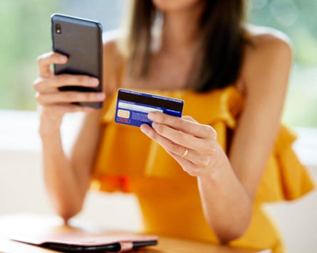 A woman on a mobile phone holding her credit card in the other hand
