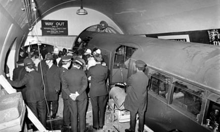 Police officers and firefighters standing in the tunnel, with the crashed train in front of them.