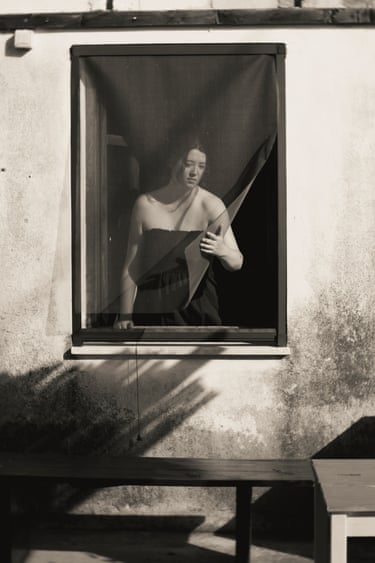 Woman holding a blind at a window