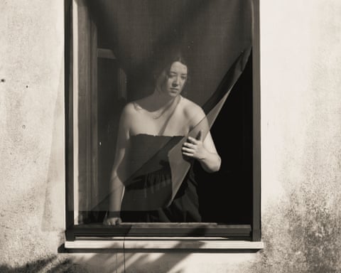 Woman holding blinds at a window