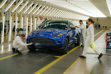 Paint technicians inspect a dark blue DBX 707 as it prepares to leave the St Athan factory in Barry, Wales.