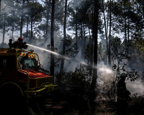 Firefighters aim a jet of water in a forested area