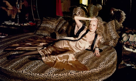 Twiggy holds back her curled blonde hair with one hand while reclining on a leopardskin bed