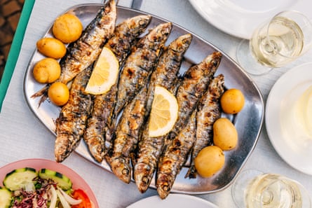 Grilled sardines with potatoes served at a restaurant, high angle close-up view