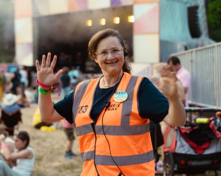 Olga, wearing a hi-vis orange jacket, waves at the camera