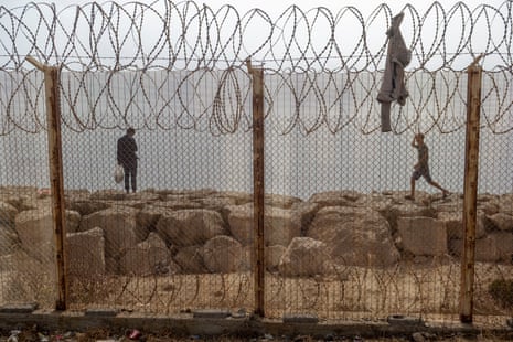 Two people stood near a barbed wire fence.