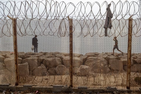 Two people stood near a barbed wire fence.