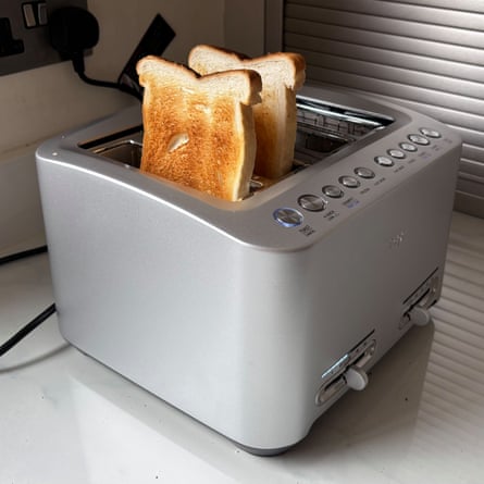 A silver Sage The Smart Toast 4 Slice Toaster with two slices of toast popping out the top on a worktop