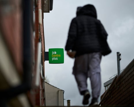 A person wearing a hooded coat walking near a jobcentre