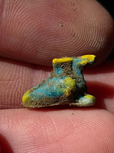 A close up of a green and yellow necklace charm being held in someone’s hand