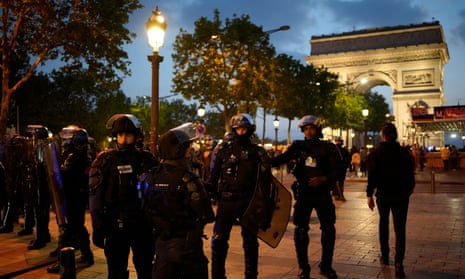 Officers in riot gear patrol in front of the Arc de Triomphe in central Paris.