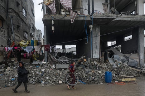 Palestinian children walk past the rubble of a destroyed buildings in the Al Nusairat refugee camp in the southern Gaza Strip.